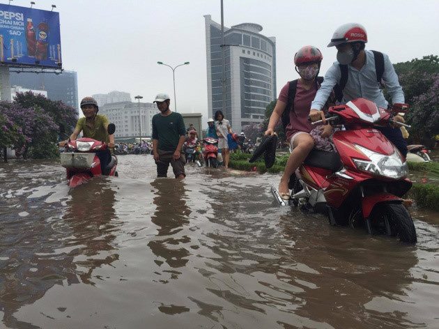 Người dân dùng xe máy để lội nước trên đường ngập