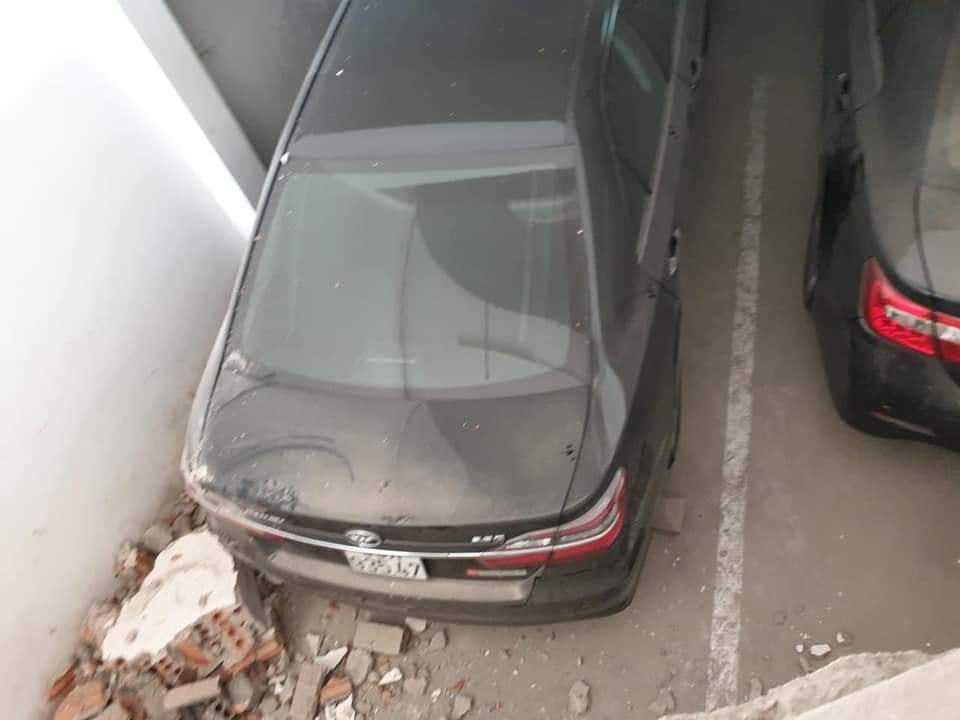 Chiếc ô tô đỗ bên dưới bị hư hỏng nhẹ đuôi xe vì mảnh vỡ của bức tường rơi trúng
