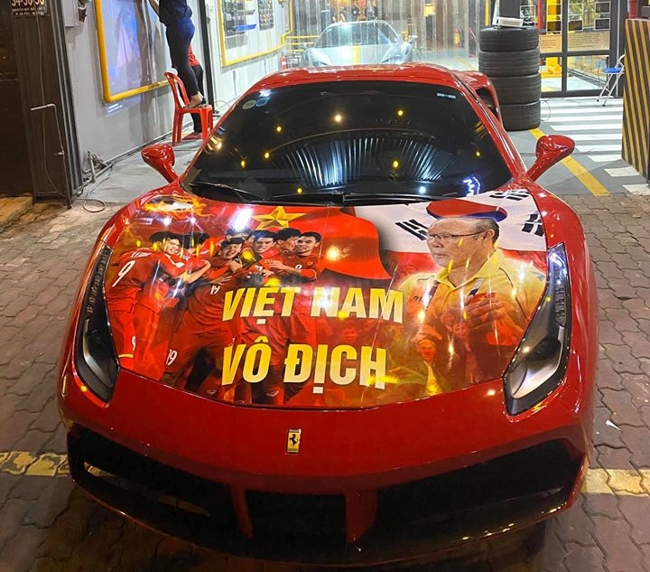 Chiếc Ferrari 488 Spider được dán bộ tem có hình ảnh và cầu thủ Việt Nam. Phía bên trong là Ferrari 458 Spider của một hot girl Sài thành